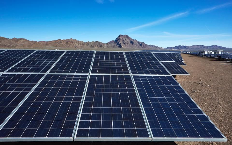 Solar panel installation in desert with mountains in background